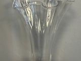 un vase en verre transparent posé sur un socle en bois, sur une table