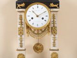 une horloge posée sur une table devant un tableau