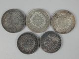 five different coins are shown in a row on a white surface