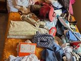 un lit sur lequel sont posés beaucoup de vêtements