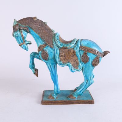 une statue bleue représentant un cheval avec une selle sur le dos