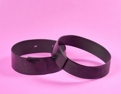 une paire de bracelets en cuir noir sur fond rose