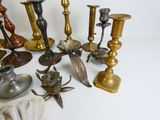 many different types of candles and candlesticks on the table