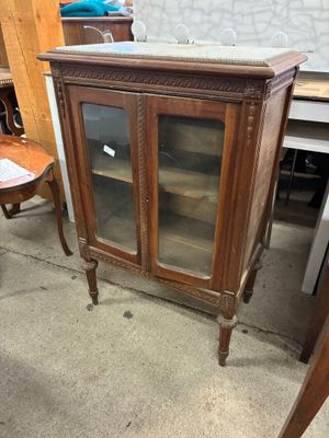 a small cabinet with a glass door in the middle of a room