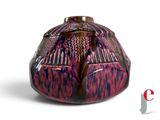 a red and black vase sitting on a white surface