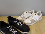 deux paires de baskets noires et blanches posées sur un parquet