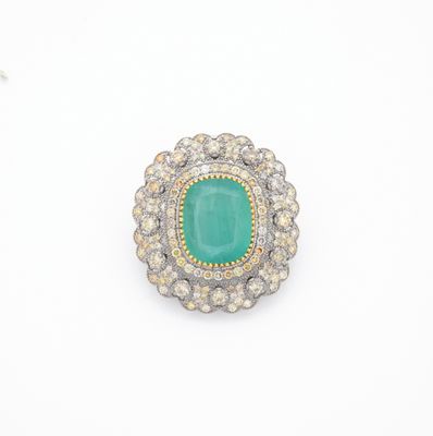 gros plan d'une bague avec une pierre verte entourée de diamants
