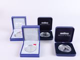 trois pièces d'argent se trouvent dans un étui bleu et une pièce d'argent se trouve dans une boîte bleue