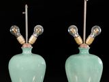 pair of green ceramic lamps on red table with black background