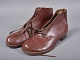 une paire de bottes en cuir marron à lacets posées sur une surface grise