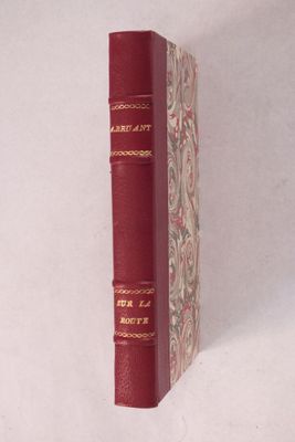 un vieux livre à la couverture rouge posé sur une surface blanche