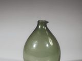 un vase en verre vert posé sur une surface blanche