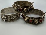 trois bracelets en argent ornés de pierres rouges et vertes