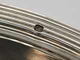 a close up of a silver plate with a hole in it