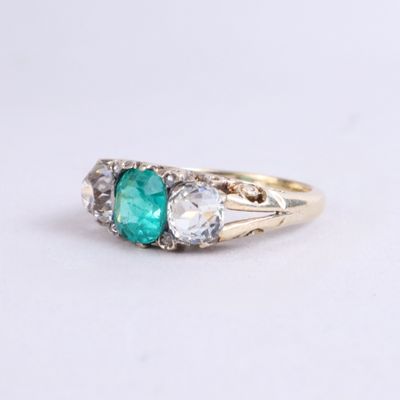 a close up of a gold ring with an emerald and white topaz