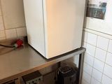 a white refrigerator sitting on a metal shelf in a kitchen