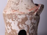a clay vase with a hole in it on a white surface