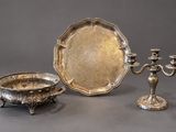 three pieces of silverware are sitting on a table next to a candle holder