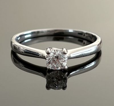 a close up of a diamond ring on a reflective surface