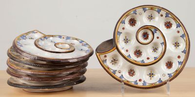 une pile d'assiettes posée sur une table, à côté d'une assiette ornée d'un motif en spirale