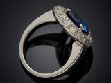 a close up of a ring with a blue sapphire and diamonds
