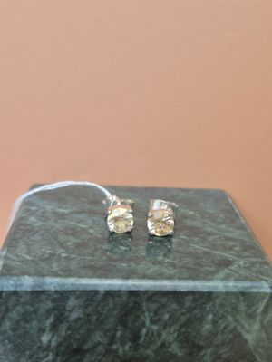 une paire de boucles d'oreilles en argent posée sur une table en marbre avec un fond rose
