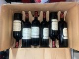 six bottles of wine are in a cardboard box on a table
