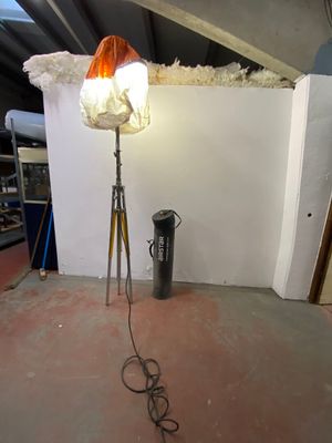 a lamp that is on a tripod next to a trash can