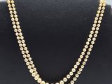 two strand pearl necklace with gold beads on a black mannequin