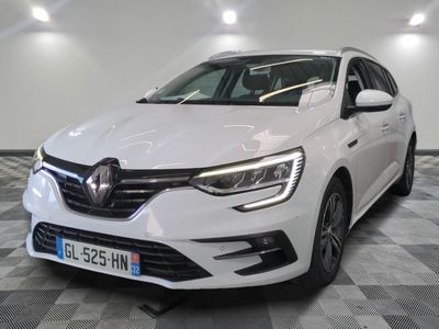 la voiture blanche est garée sur un sol en damier dans le garage
