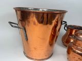 two copper pots and a vase on a white surface