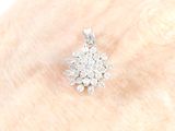 an image of a woman ' s hand with a diamond flower pendant on it