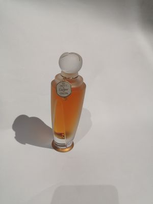 un petit flacon de parfum posé sur une surface blanche