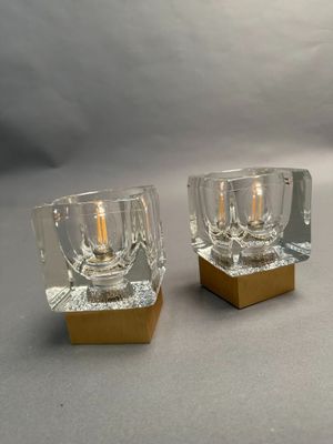 two glass candle holders with a gold base on a table