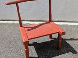 une chaise rouge posée sur le trottoir devant un mur blanc
