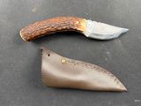 a knife that is laying on a table next to a leather case