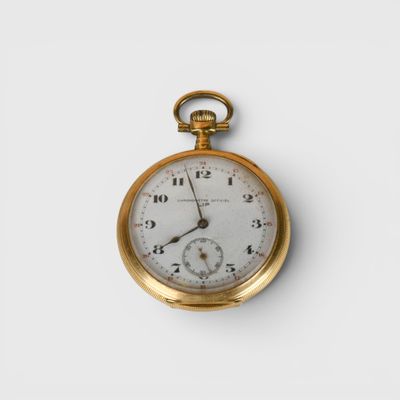 une montre de poche en or avec un cadran blanc sur une surface blanche