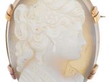un gros plan du visage d'une femme sur une broche en forme de coquillage