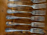 a lot of forks that are on a wooden table