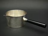 une casserole en argent avec une poignée noire posée sur une table noire