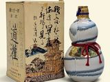 une petite bouteille décorée d'un motif, à côté d'une boîte