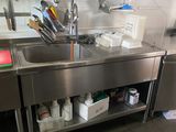 un grand évier en inox dans une cuisine remplie d'ustensiles