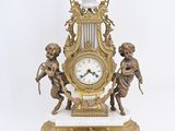 a gold clock on a marble base with angels around it