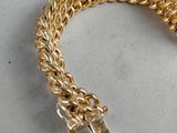 a close up of a gold chain bracelet on a white surface