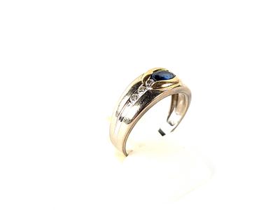 un gros plan d'une bague posée sur une surface blanche, ornée d'une pierre bleue