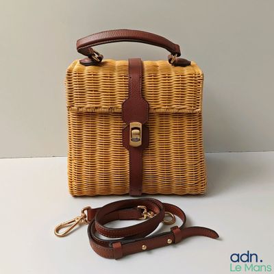 sac en osier marron avec une anselle en cuir marron sur un fond blanc