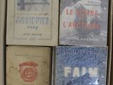 Plusieurs livres sont empilés dans une boîte en carton posée sur une table