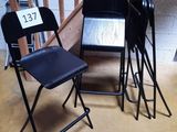trois chaises pliantes noires placées les unes à côté des autres dans une pièce