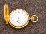 une montre de poche en or posée sur une surface marron