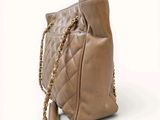 beige leather handbag with gold chain strap on a white background